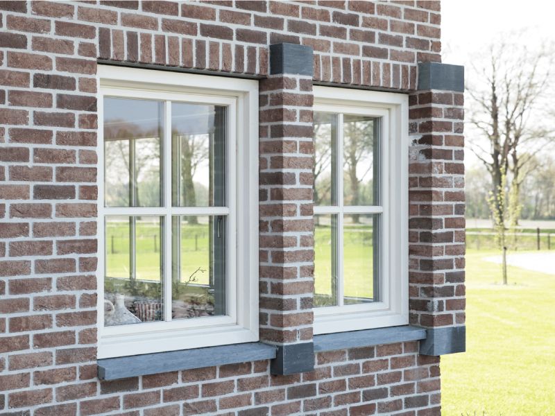 Kwaliteit kunststof Bakstenen gevel van woning in landelijke omgeving voorzien van kunststof kozijnen.